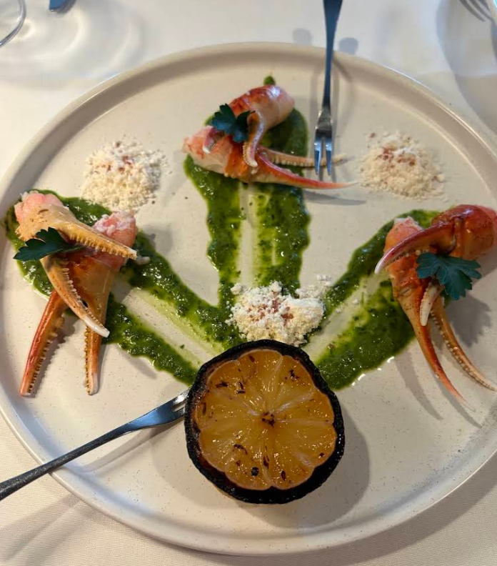 Snow crab claws plated with charred lemon, Fine Herbs Vinaigrette and Butter Powder